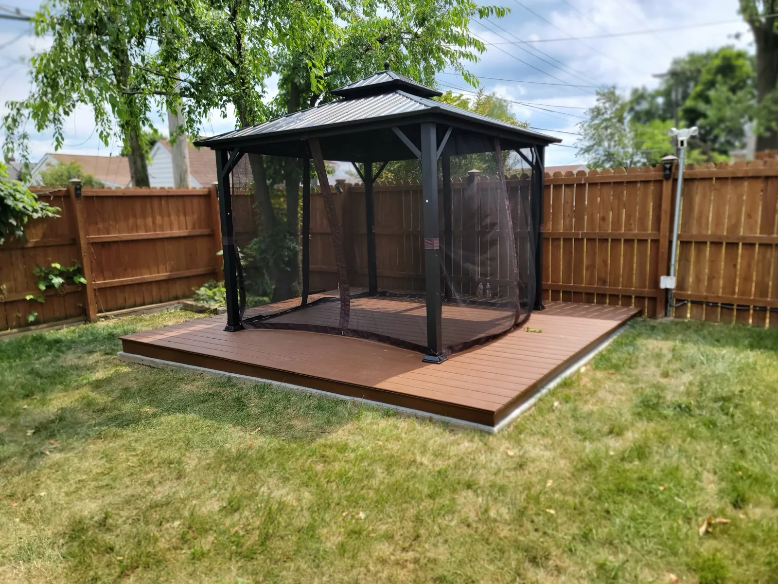 Screened gazebo installed on a backyard deck